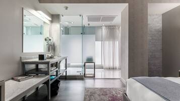 Een moderne hotelkamer met een groot bed, een kaptafel met spiegel, een douche en uitzicht op de stad.