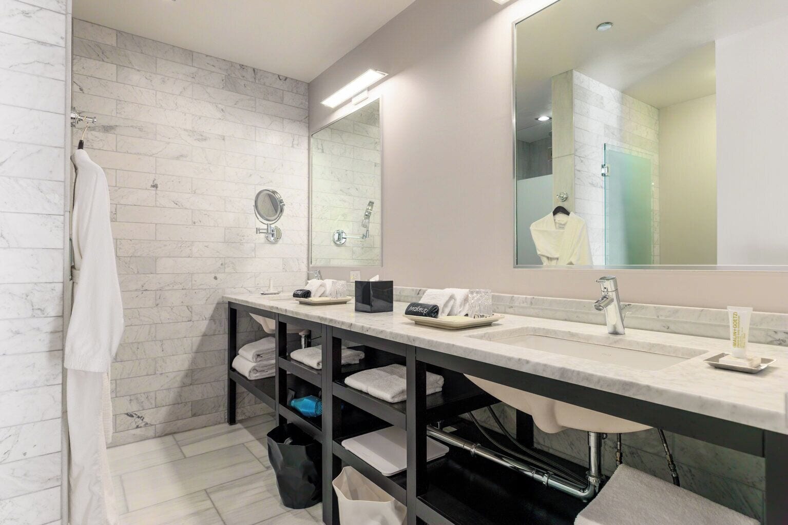 Un baño moderno con tocador de mármol, un espejo grande y un perchero.