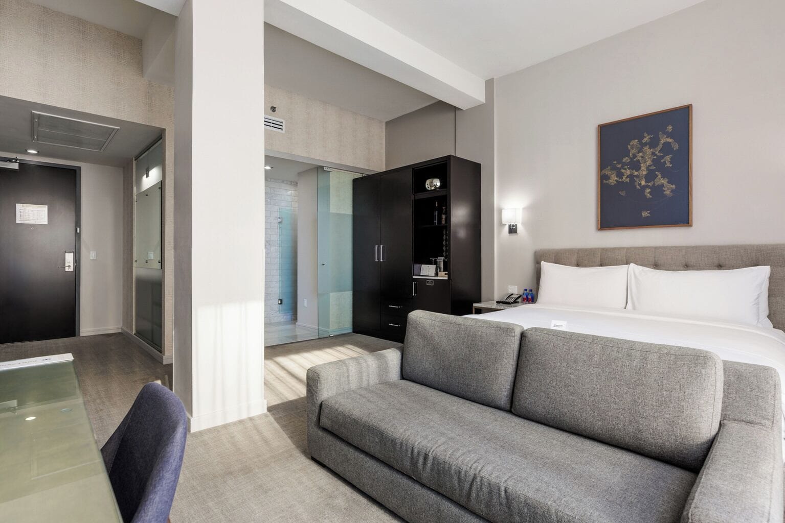 Een hotelkamer met een bed, een bank, een bureau en een kledingkast.