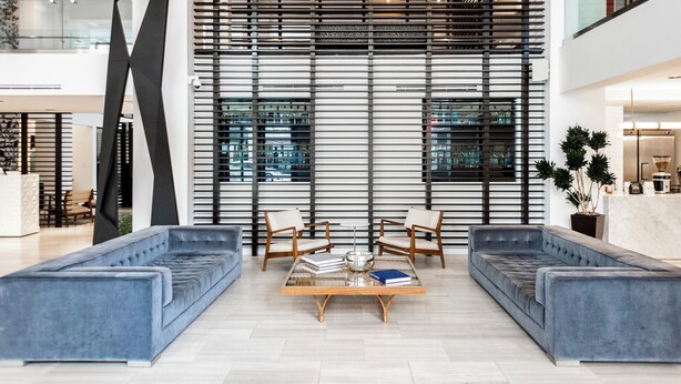 Een moderne woonkamer met een hoekbank, twee fauteuils en een glazen salontafel.