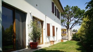 Ein modernes Haus mit großen Fenstern, einem gepflegten Rasen und Kübelpflanzen.