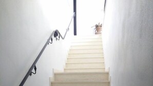 Eine Treppe mit Geländer auf der linken Seite, die zu einer Zwischenebene mit einem Blumentopf führt.