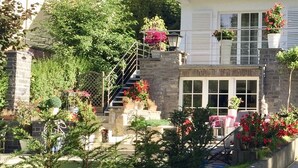 A two-story house with a stone facade, a red-tiled roof, and a balcony with potted plants. - Exclusive Flats Studio Swimming-pool (Dilbeek)