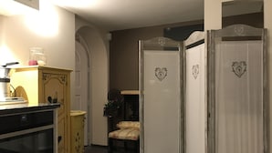 A room with a kitchen area, a yellow cabinet, a chair, and a wardrobe with heart designs. - Exclusive Flats Studio Swimming-pool (Dilbeek)