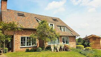 A two-story brick house with a tiled roof, large windows, and a well-maintained garden.