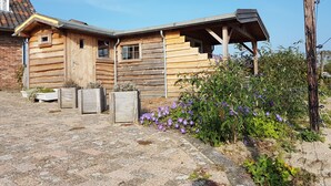A rustic wooden cabin with a porch and a stone-paved entrance. - Aan de Waterspiegel (Aagtekerke)