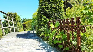 A cobblestone pathway leading to a rustic gate with intricate metalwork. - Aan de Waterspiegel (Aagtekerke)