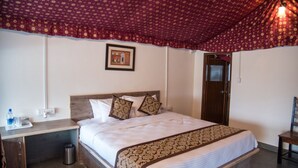A hotel room with a bed, a nightstand, a trash bin, a framed picture on the wall, and a door.