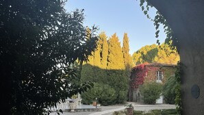 An arched stone pathway leading to a building with a window, surrounded by trees and shrubs. - Hôtellerie du Château de Floure & Spa (Floure)