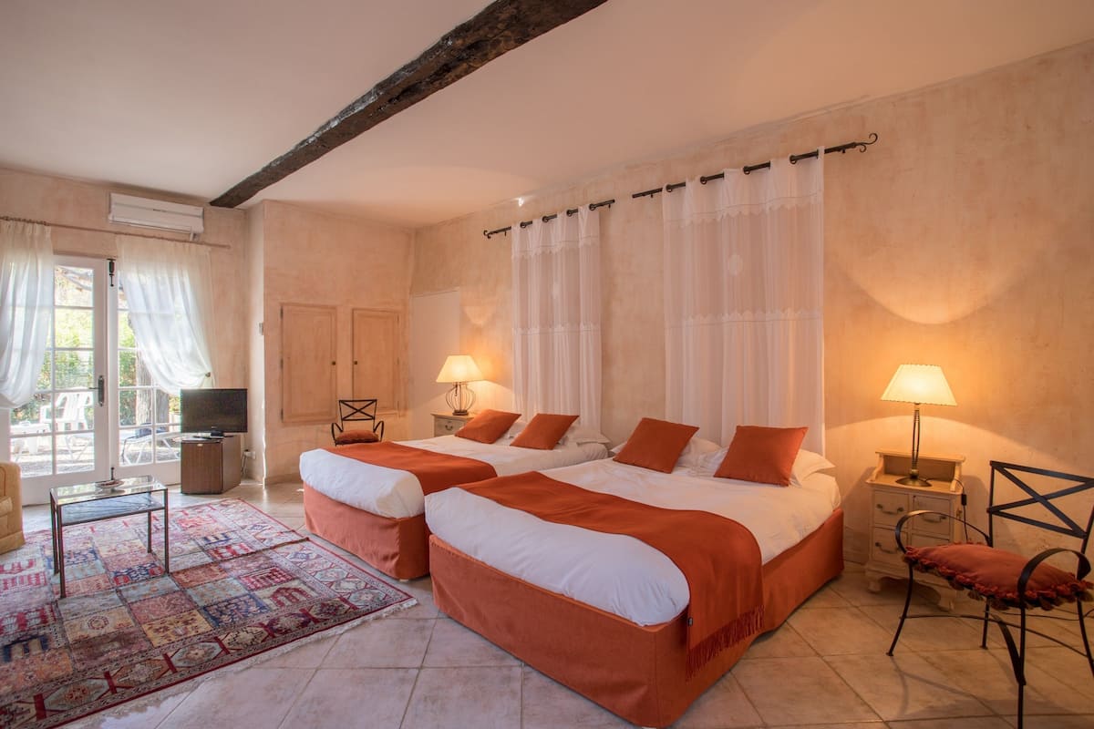 A hotel room with two beds, a TV, a desk, and a chair.