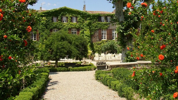 A garden pathway leading to a building with a brick facade and green vines. - Hôtellerie du Château de Floure & Spa (Floure)