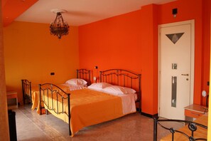 Ein Zimmer mit zwei Betten, einer Chandelier, einer Tür mit einer dreieckigen Verzierung und einem kleinen Tisch.