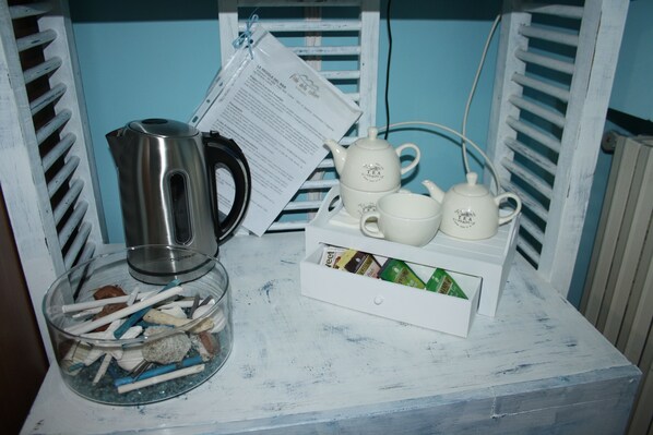 A white table with a glass ashtray, a stainless steel kettle, and a white tray with tea cups and a teapot. - B&B Viale delle Colline (Salerno)