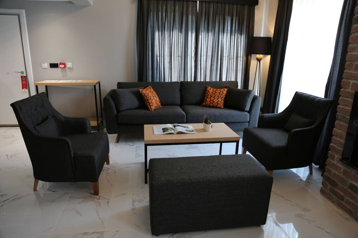 Una sala de estar moderna con un sofá, dos sillones, una mesa de centro y una mesita auxiliar.
