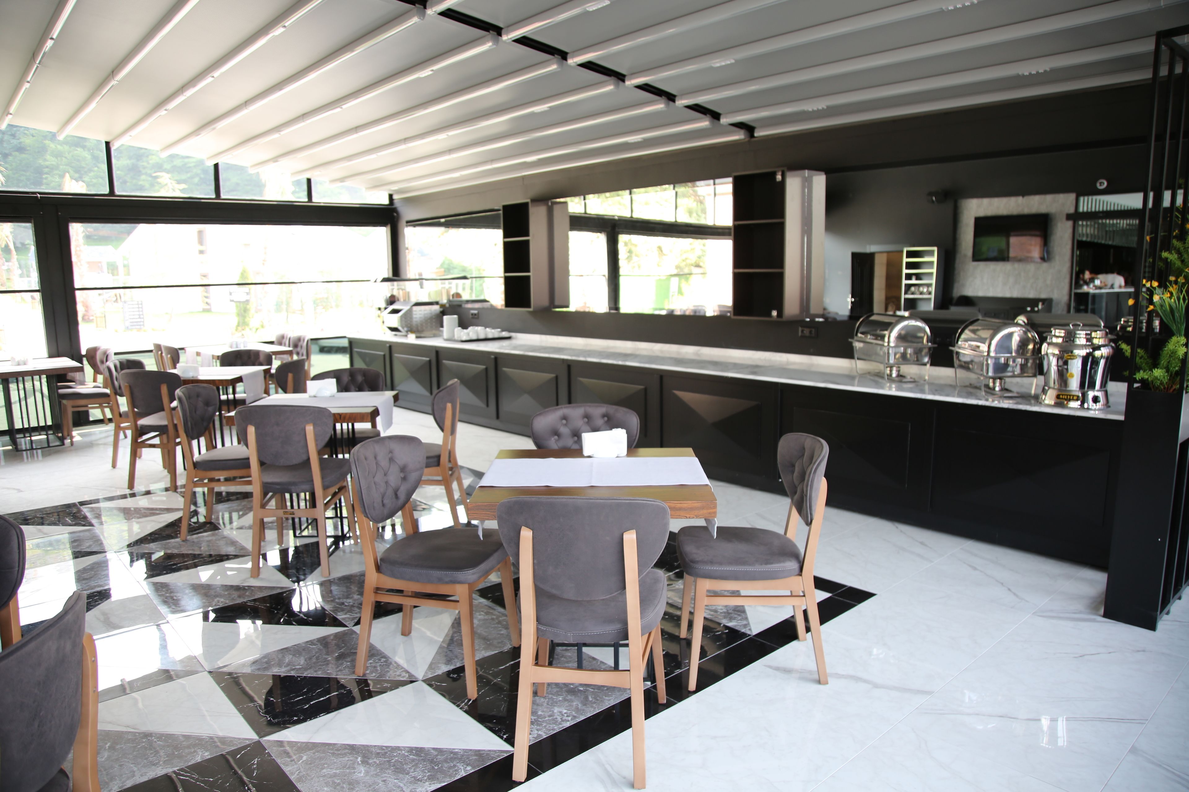 A modern restaurant with a bar area, large windows, and a mix of wooden and upholstered chairs.