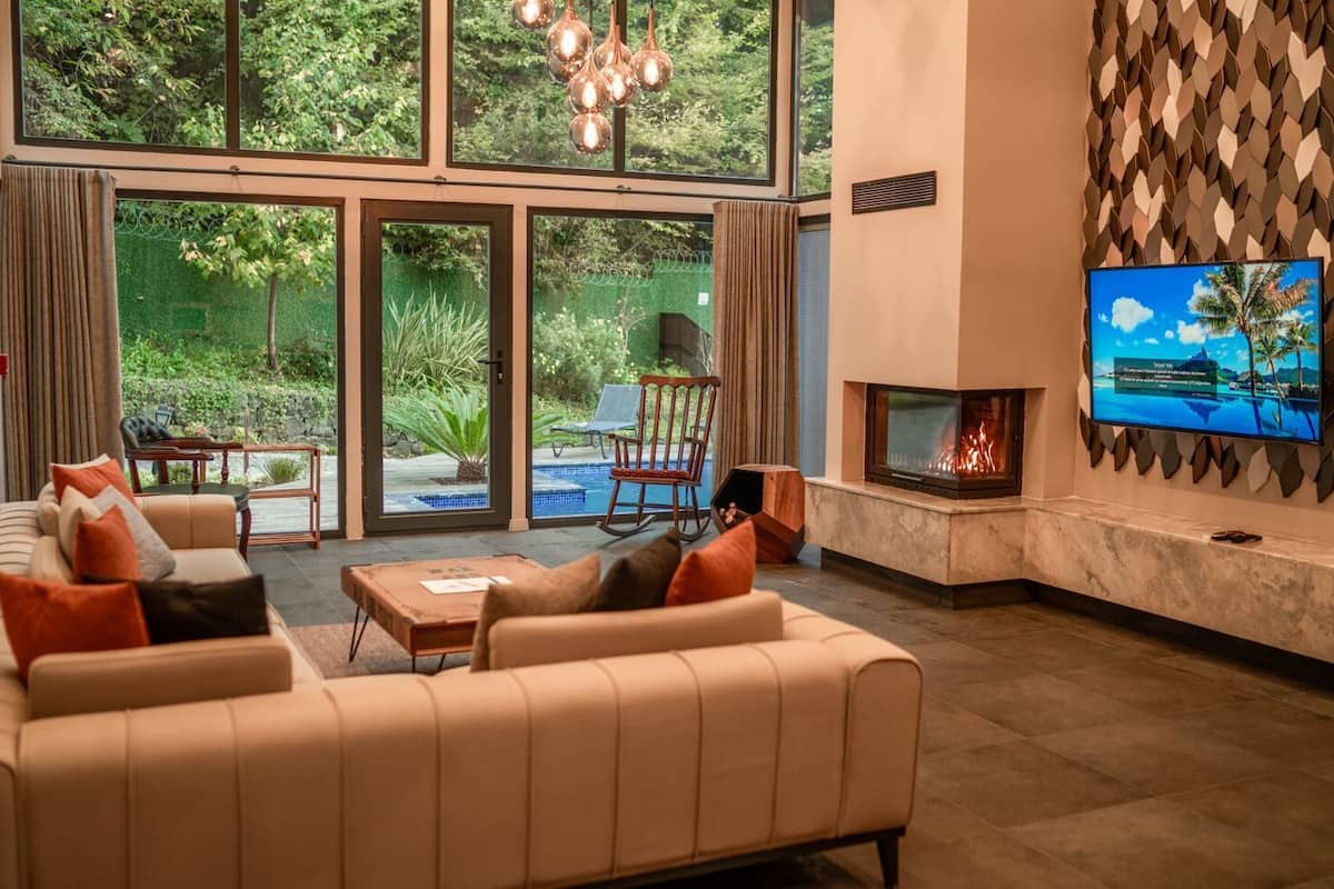 Una sala de estar moderna con un sofá grande, una chimenea y un televisor montado en la pared.