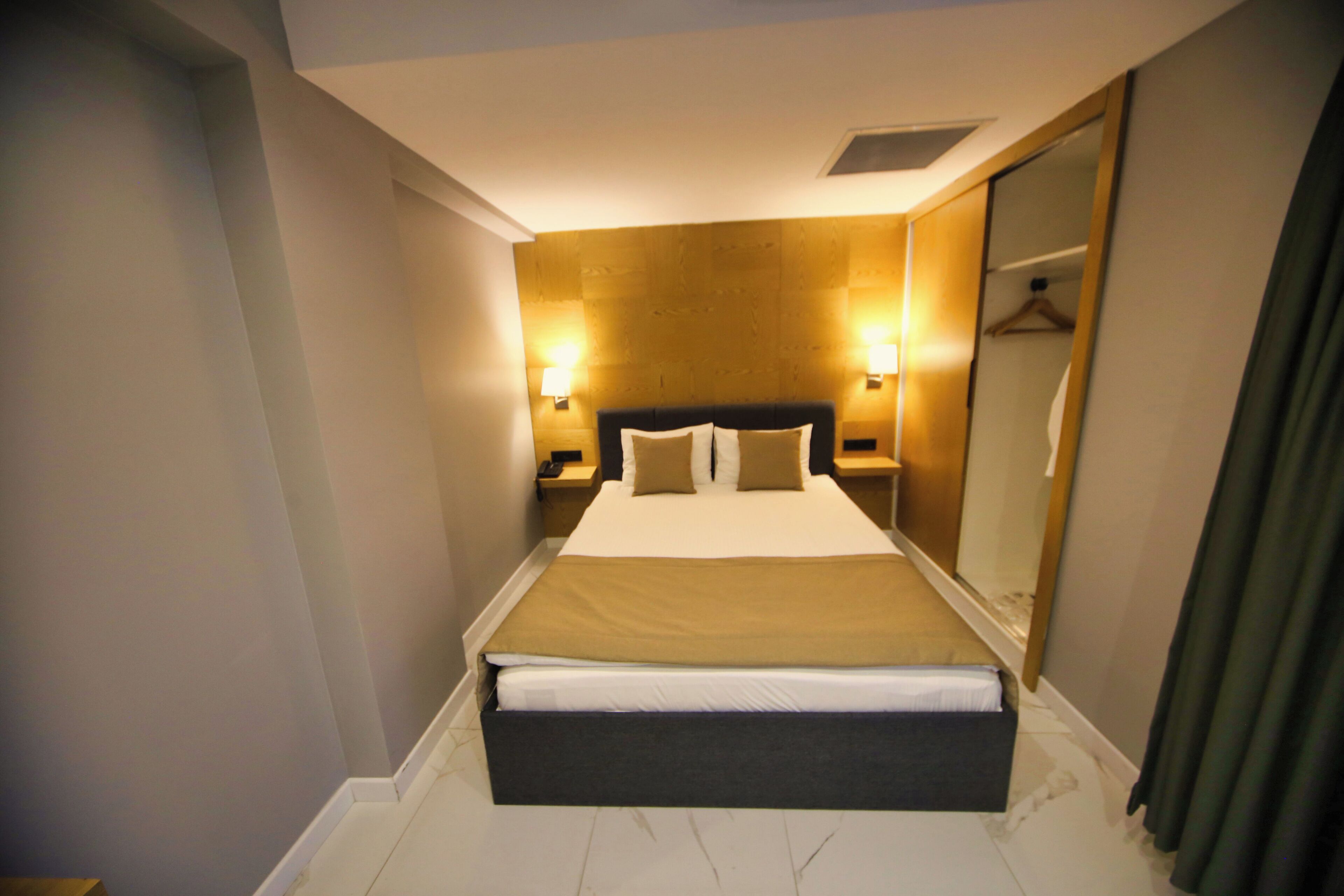 Une chambre d’hôtel avec un grand lit, deux tables de chevet, un miroir et un dressing.
