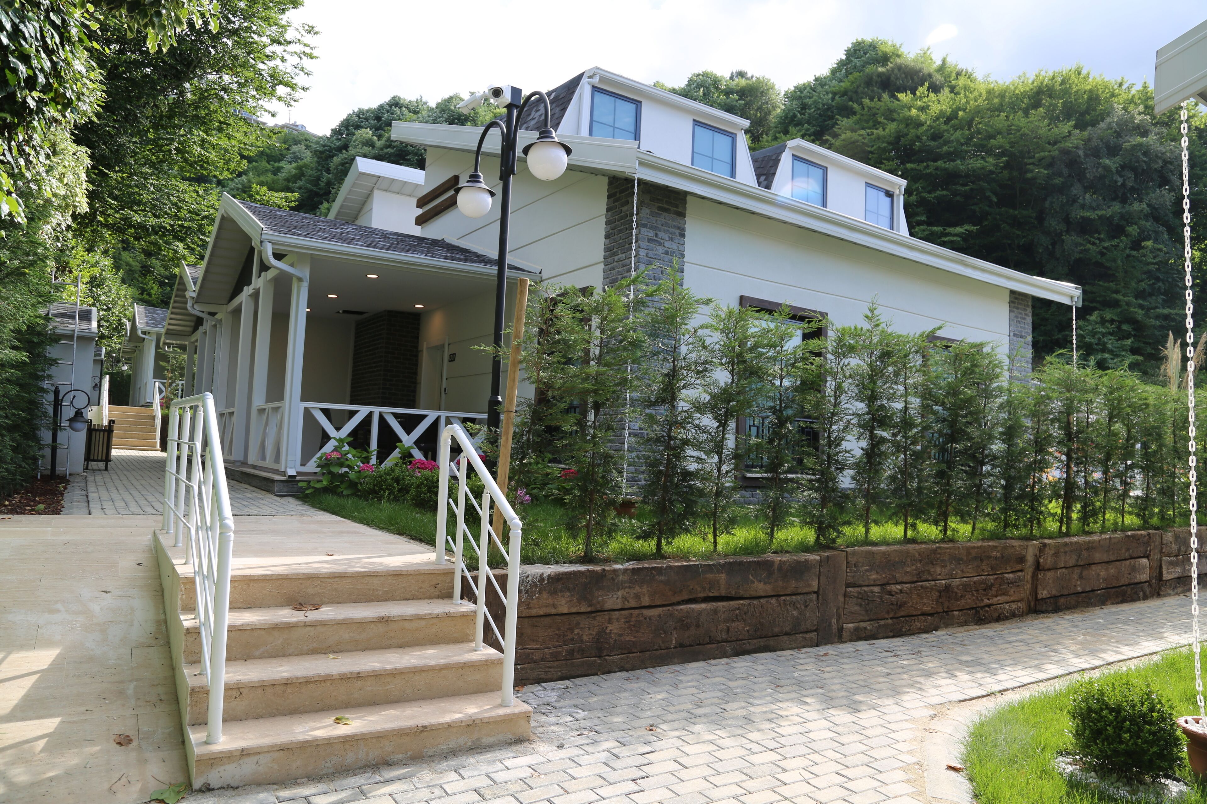 A modern house with a covered porch, a staircase with a white railing, and a brick pathway.