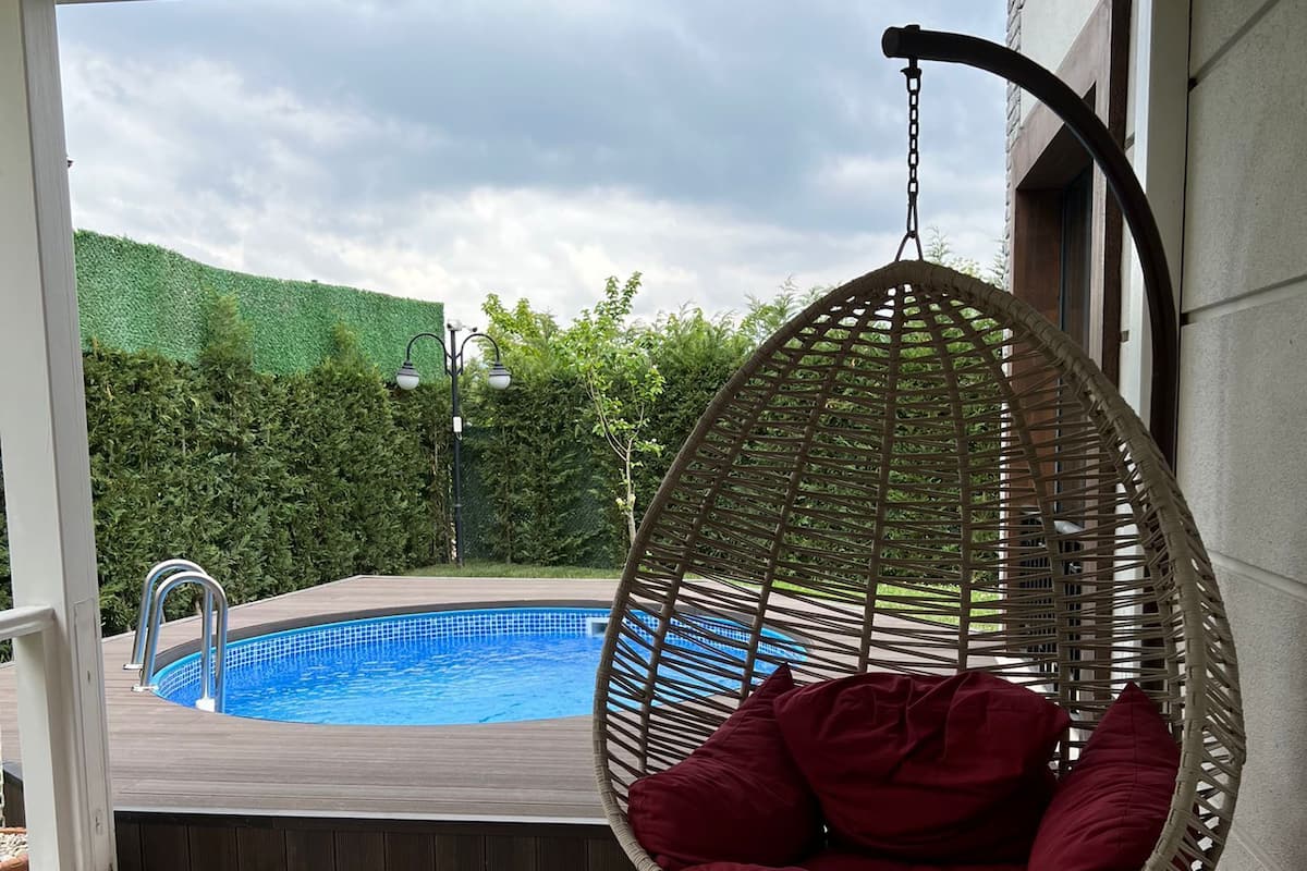 Un área junto a la piscina con una hamaca colgante y una pileta.