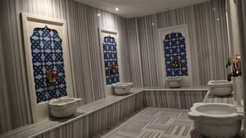 Bathroom features three toilets, three sinks, and a geometric tile floor.