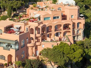 A multi-story hotel with balconies, outdoor seating, and a pool.