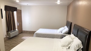 A hotel room with two beds, a wardrobe, and an air conditioning unit. - Topper Motel (Taft)