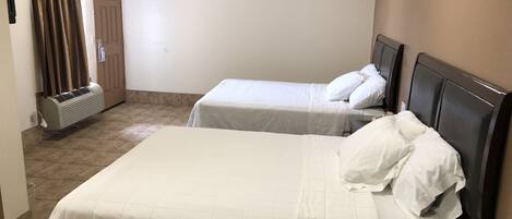 A hotel room with two beds, a wardrobe, and an air conditioning unit.