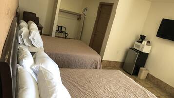 Habitación de hotel con dos camas, un refrigerador pequeño, microondas y televisión en la pared.