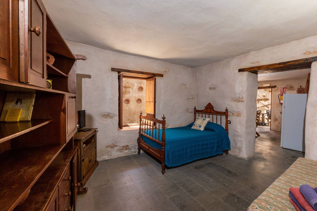A bedroom with a wooden bed, a small desk, and a window.
