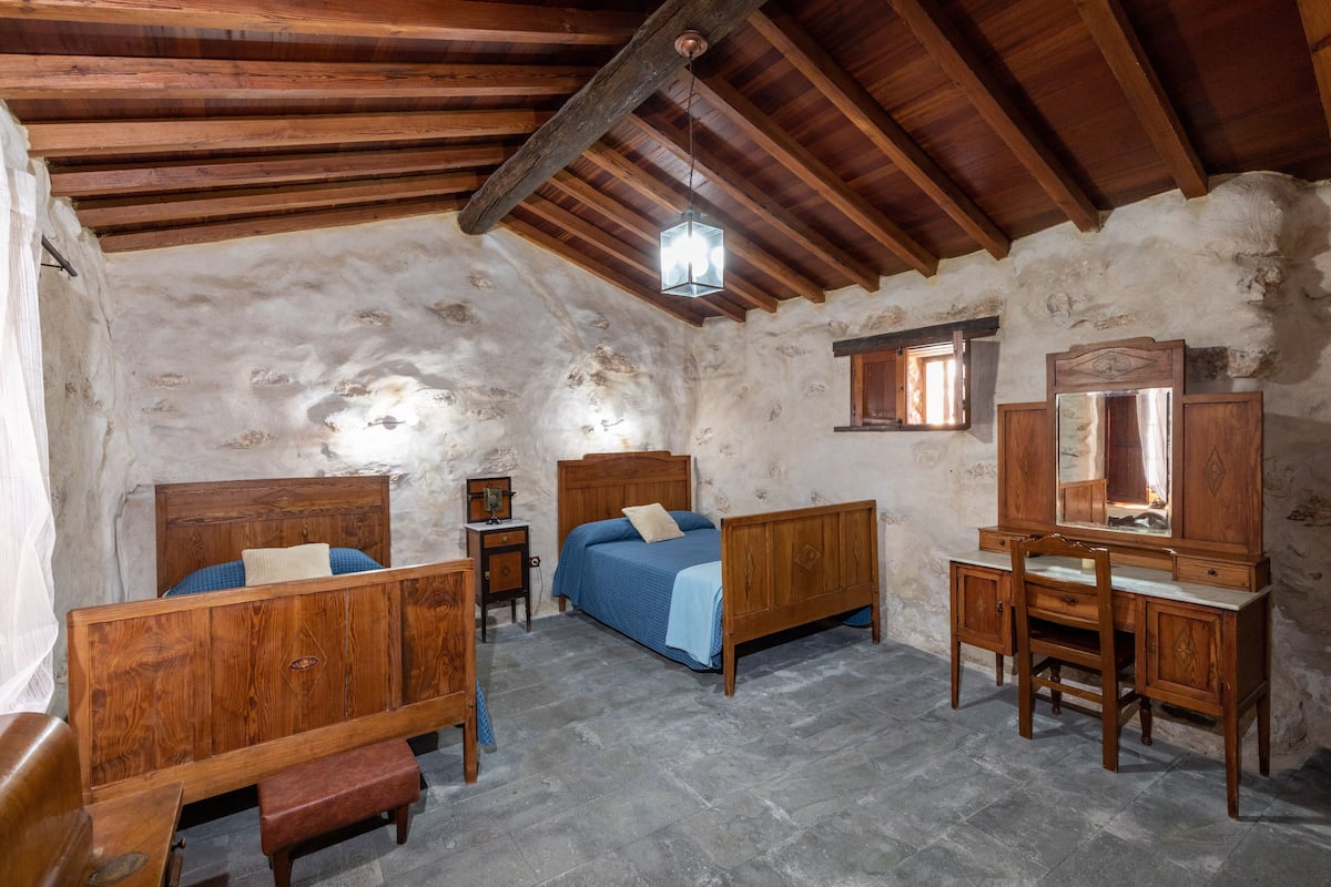 A rustic room with wooden furniture, a bed, a desk, and a mirror.