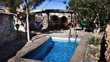 Una piscina al aire libre, sillones reclinables de piscina