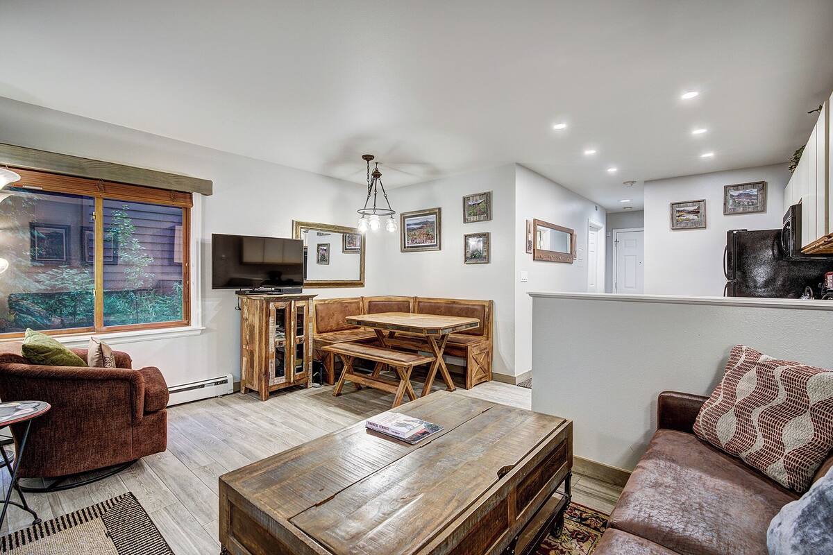 A cozy living room with a wooden coffee table, a sofa, a dining table with chairs, and a television.