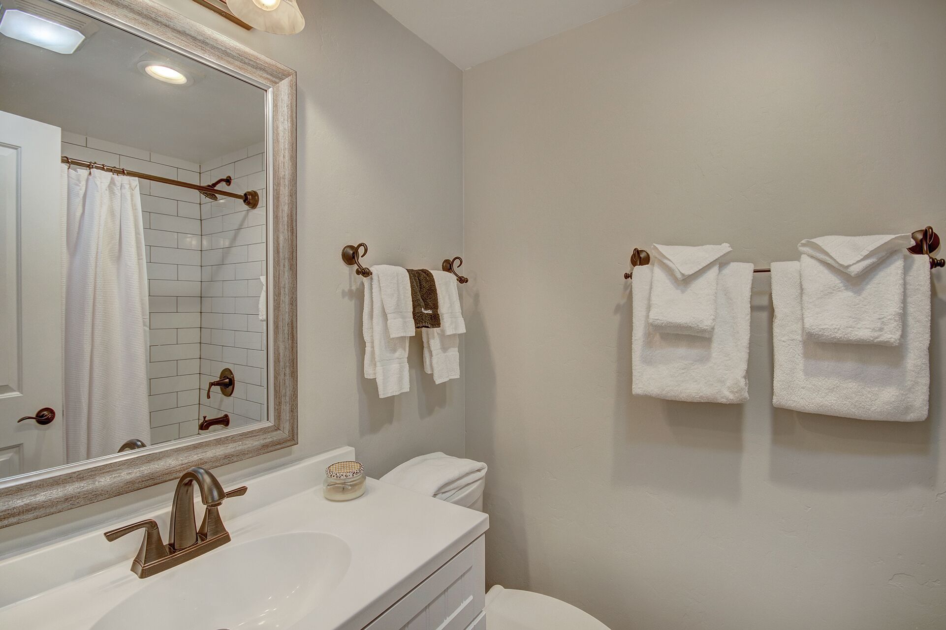 A bathroom with a white sink, a mirror, and two towel racks with white towels.