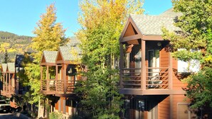 A row of wooden cabins with balconies, surrounded by trees and a clear sky. - Wildwood Lodge Downtown Condos with Hot Tub (Breckenridge)