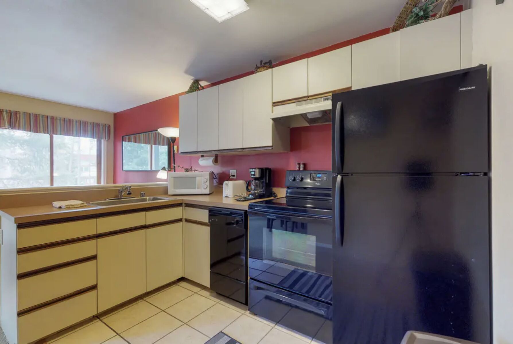 A compact kitchen with a black refrigerator, a microwave, a coffee maker, and a dishwasher.