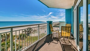 Een balkon met uitzicht op strand en zee.