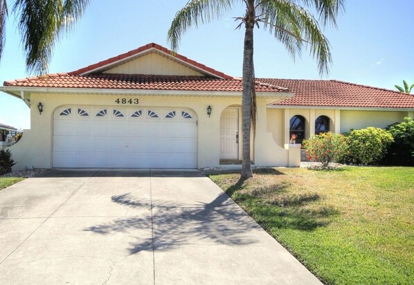 A single-story house with a red-tiled roof and a white garage door.