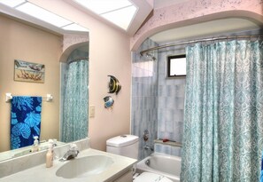 A bathroom with a large mirror, a bathtub, a toilet, and a shower curtain.