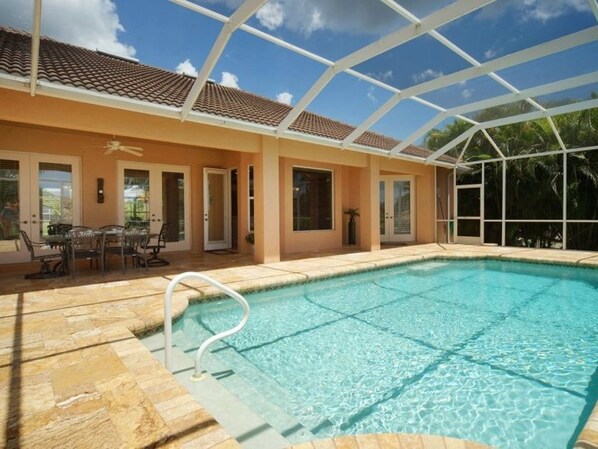 A swimming pool with a glass roof, surrounded by a patio area with outdoor furniture.