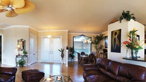 A spacious living room with a brown leather sofa, a coffee table, and a ceiling fan. - Bahama by 123cape VR (Cape Coral)