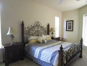 A bedroom with a bed, nightstands, lamps, a framed picture on the wall, and a window with blinds.