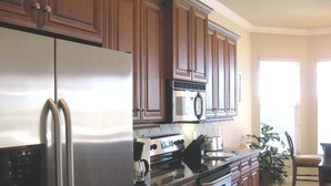 A kitchen with wooden cabinets, stainless steel appliances, and a large island with a sink. - Bahama by 123cape VR (Cape Coral)