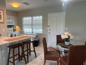 Enjoy meals in the kitchen and dining area, featuring a stove, microwave, and round table with wicker chairs.