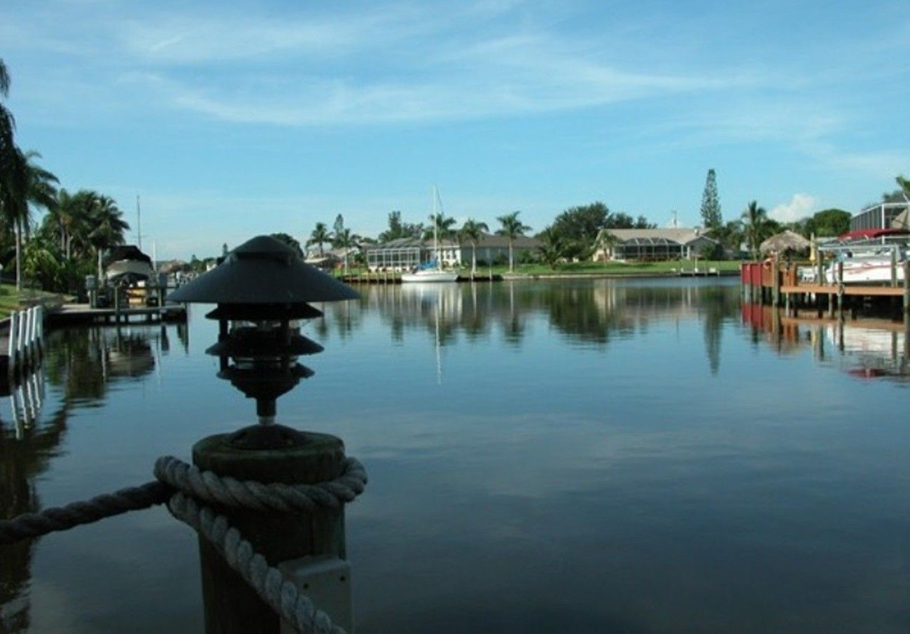 Un paysage paisible au bord de l’eau, avec un quai, un bateau et une maison en arrière-plan.