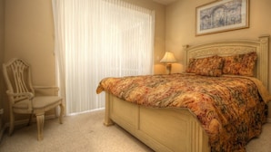 A bedroom with a bed, a chair, a ceiling fan, and a painting on the wall. - American Dream by 123cape VR (Cape Coral)