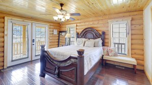 Ein Schlafzimmer in einer Blockhütte mit einem hölzernen Bett, einer Bank und einem Deckenventilator.