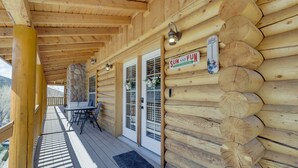 Eine Blockhütte mit überdachter Veranda, einem Kamin aus Stein und einem Schild mit der Aufschrift 'SUN AND FUN'.