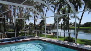 A swimming pool with a clear view of a lake and palm trees in the background.