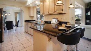 A modern kitchen with a central island, pendant lighting, and a view to the outdoors.