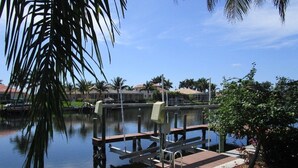 A calm water body with a dock, palm trees, and a clear sky.